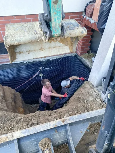 Rozwijanie folii kubełkowej w wykopie przy ścianie fundamentowej